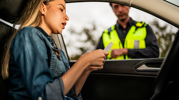 Women reading a traffic ticket while speaking to a police officer at her vehicle