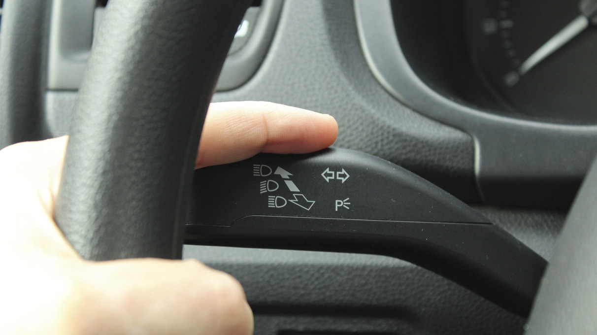 Someone with their finger on the signal lever in a car