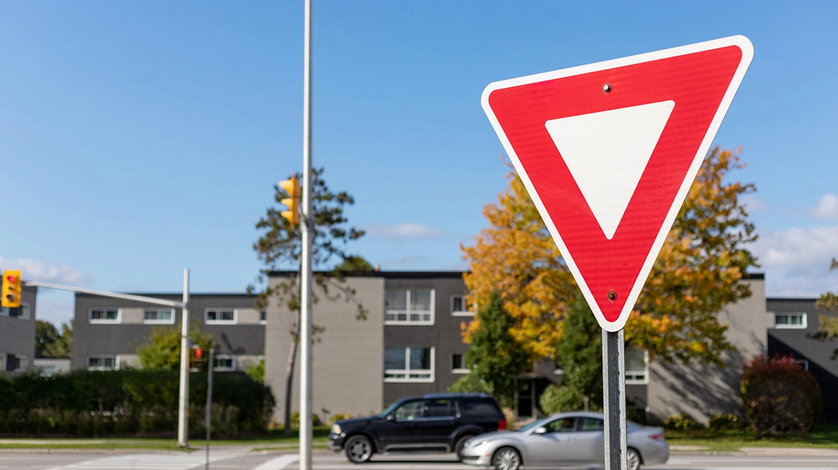 Yield sign with a road and vehicle in the background