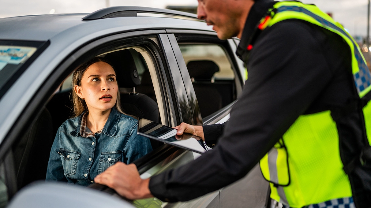 Police officer checking a driver at a roadside traffic stop.