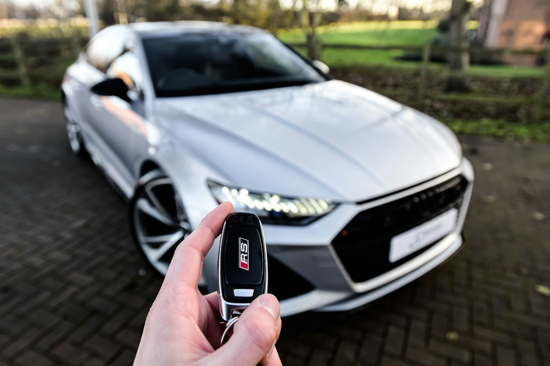 Driver holding a car key in front of a vehicle.